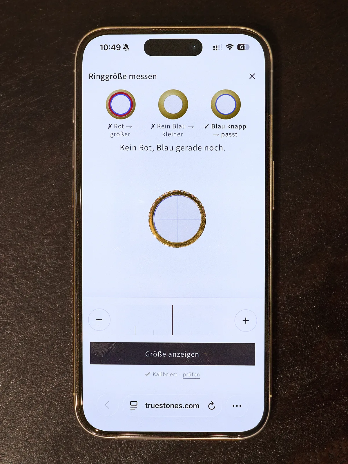 Smartphone mit dem Ringgrößen-Tool von Truestones, ein Goldring liegt zum Messen auf dem Messkreis am Bildschirm