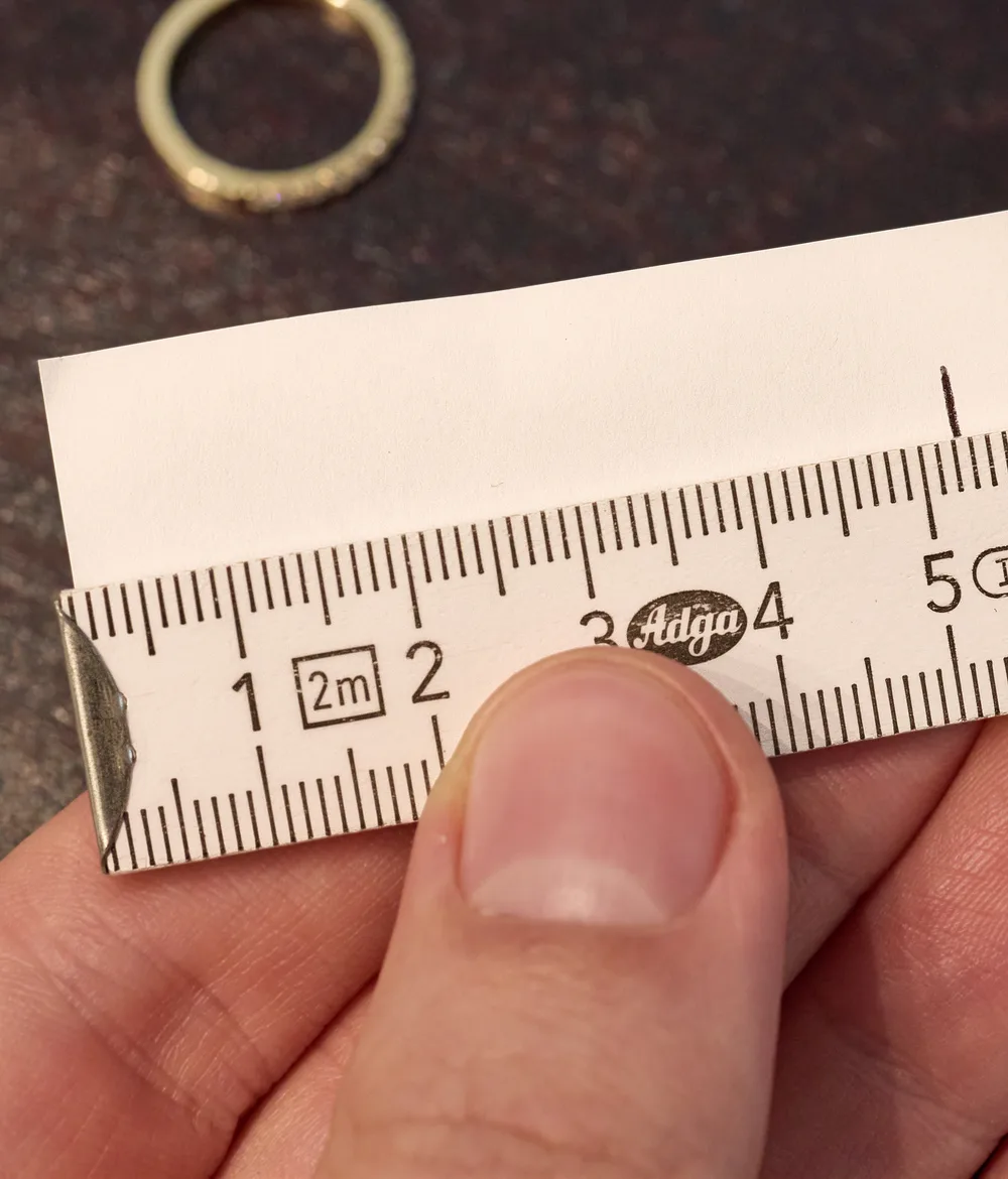 Der ausgerollte Papierstreifen liegt am Meterstab, die Strecke bis zur Markierung ist der Innenumfang des Rings in Millimetern